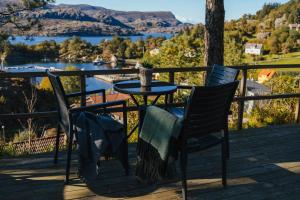 a table and chairs on a deck with a view of a lake at Solund Leileghetshotell in Hardbakke +48 photos