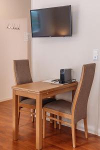 a wooden table with two chairs and a television on a wall at Solund Leileghetshotell in Hardbakke