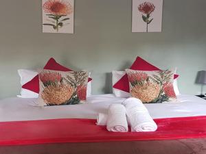 a bed with red and white pillows and towels on it at Bella Rosa Cottage in Clarens +2 photos