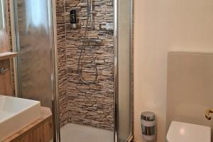 a bathroom with a shower with a stone wall at Wohnung 10 im Haus Hühnergott im Seepark in Ostseebad Sellin +29 photos