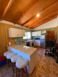 a kitchen with a counter and stools in a room at Cabaña en el Campo de Villarrica in Huiscapi