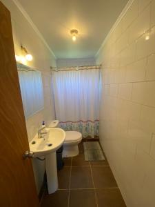 a bathroom with a white sink and a toilet at Cabaña en el Campo de Villarrica in Huiscapi