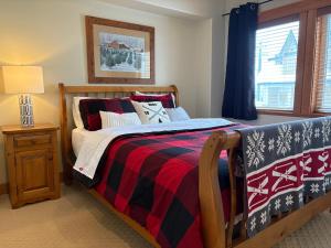 - une chambre avec un lit doté d'une couverture rouge et noire dans l'établissement Gone Ski 'Inn, à Big White