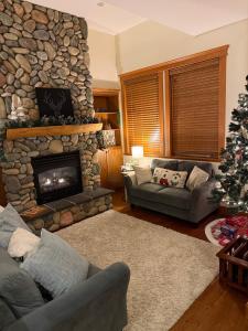 un salon avec une cheminée en pierre et un sapin de Noël dans l'établissement Gone Ski 'Inn, à Big White