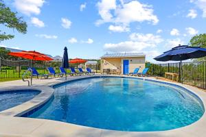 a swimming pool with chairs and umbrellas at Hill Country Casitas in Dripping Springs