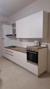 une cuisine avec des armoires blanches et un four à plaques de cuisson dans l'établissement La casa di Titty, à Reggio de Calabre