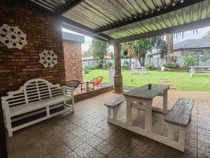 a patio with benches and a table and a brick wall at Zhantique Guest House 2- Unit 12 in Boksburg +8 photos