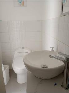 a white bathroom with a toilet and a sink at Lugar encantador junto al mar in Pacasmayo