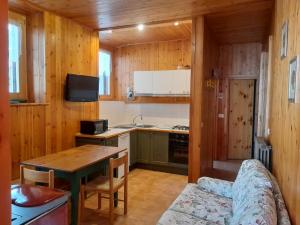 a kitchen with wooden walls and a table and a couch at Appartamenti Via Monte Braulio 19 in Bormio
