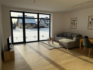 a living room with a couch and a large window at Apartamenty pod sosną in Zakrzewo