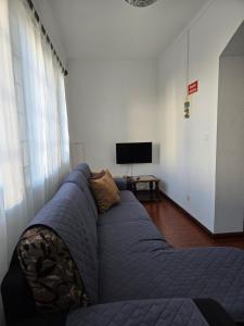 a living room with a blue couch and a tv at Casa do Avô Silva in Santa Cruz das Flores