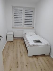 a white bedroom with a bed and a wooden floor at Haus Blankenagel 2 in Hagen