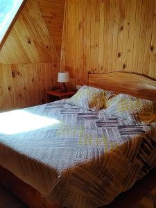 a bedroom with a bed with a wooden wall at Los Cipreses in Ancagual