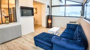 a living room with a blue couch and a tv at Gite L'écrin du château in Polignac