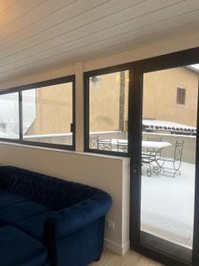 un salon avec un canapé bleu et un patio dans l'établissement Gite L'écrin du château, à Polignac