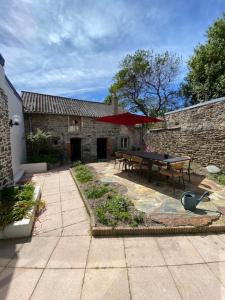 eine Terrasse mit einem Tisch und einem roten Regenschirm in der Unterkunft Maison de vacances hyper centre, plage à pied - Etables sur Mer in Étables