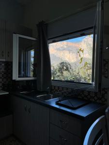 a kitchen with a sink and a large window at Grekou Farmhouse in the waves in Áyioi Apóstoloi