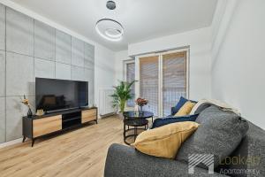 a living room with a couch and a flat screen tv at Diasfera Premium by LookAp in Łódź