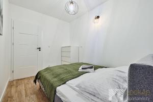 a bedroom with white walls and a bed with a green blanket at Diasfera Premium by LookAp in Łódź