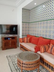 a living room with a couch and a tv at Villa Azur Haouaria in Sidi Amor