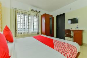 a bedroom with a large bed with a red and white blanket at Super Hotel O Tyche Stays in Trivandrum +26 photos