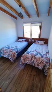 two beds in a bedroom with wooden floors at Cabaña Playa Rosada in Valdivia