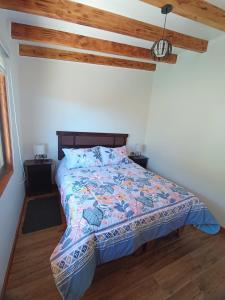 a bedroom with a bed with a colorful comforter at Cabaña Playa Rosada in Valdivia