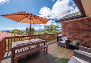 una terraza de madera con mesa y sombrilla en Sea Breeze, en Mapua