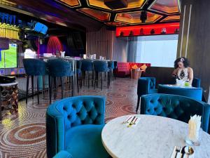 a restaurant with blue chairs and a woman sitting at a table at The Suites At Platinum KLCC in Kuala Lumpur