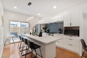 a kitchen with white cabinets and a large island with bar chairs at 3 BDRM 2 and a Half Bath - House Private Yard Duplex in Pittsburgh