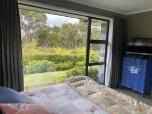 ClevedonHunua Hideaway的一间带床和大窗户的卧室