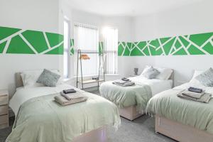 a room with three beds with green and white at Contractor Luxury Home - Long Stays - 4 Bedrooms - Sleep 8 - Zip & Link Beds - Ultra Fast WiFi - Free Parking in Birkenhead