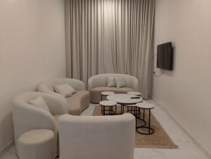 a living room with two chairs and two tables at الوعل للشقق الفندقية بالارطاوية in Al Arţāwīyah