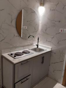 a white kitchen with a sink and a mirror at الوعل للشقق الفندقية بالارطاوية in Al Arţāwīyah +16 photos