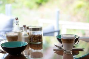 a table with two cups of coffee and bowls of food at Sungate on Salt Spring - Luxurious Suite with Cedar Hot Tub & View in Salt Spring Island