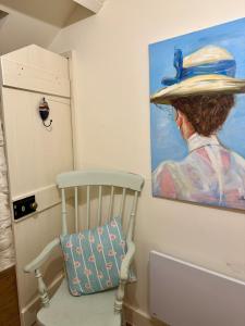 a painting of a woman with a hat on a wall at Little Cottage, Llwyngwril in Llwyngwril