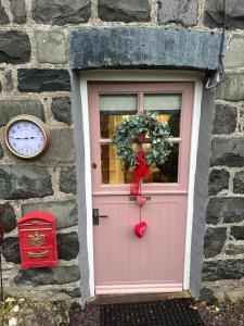 a pink door with a wreath and a clock at Little Cottage, Llwyngwril in Llwyngwril