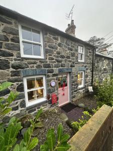 a stone house with a pink door at Little Cottage, Llwyngwril in Llwyngwril