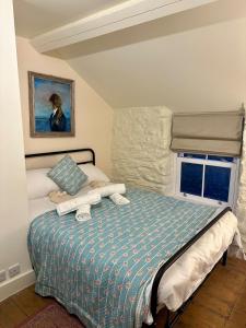 a bedroom with a bed with a blue comforter and a window at Little Cottage, Llwyngwril in Llwyngwril +20 photos