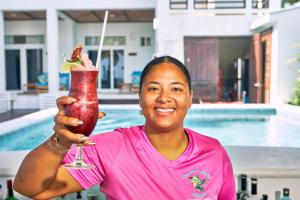 a woman is holding up a drink in front of a pool at Ocean Breeze in Placencia