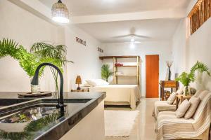 a kitchen with a sink and a living room with a bed at Casa Ravenala in Trancoso
