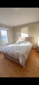 a bedroom with a bed with white sheets and a window at Church Bay House in Rathlin Island