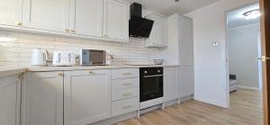 a white kitchen with white cabinets and a microwave at Milton Keynes 3BR,Spacious Home, Sleeps 5, Families Stay, Free Parking in Milton Keynes