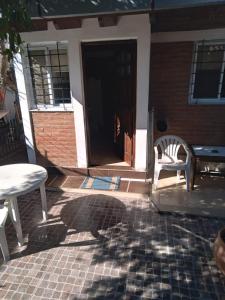 a front door of a house with a table and a chair at Departamentos Calamuchita in Santa Rosa de Calamuchita