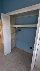 einen Schrank mit weißen Regalen und einer blauen Wand in der Unterkunft Caribbean Sea View Cottage in Saint Mary