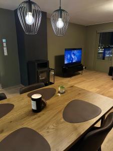 a room with a wooden table with chairs and a television at Modern apartement with parking in Kvaloysletta