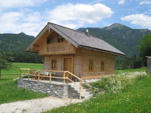 a small wooden house in a field with mountains at Ferienhütte Wolfgangsee in St. Wolfgang