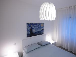 ミラノ-リスト	にあるNovegro Apartment Milano Linateの白いベッドルーム(ベッド1台、シャンデリア付)