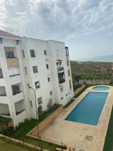an apartment building with a swimming pool in front of it at Golf & sea view appartement in Marina golf Asilah in Asilah