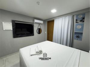 a bedroom with a bed with a television and towels at Paradise Pé na Areia -Bessa, LikeHome in João Pessoa